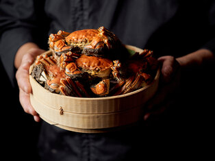 man holding a basket of steamed hairy crabs