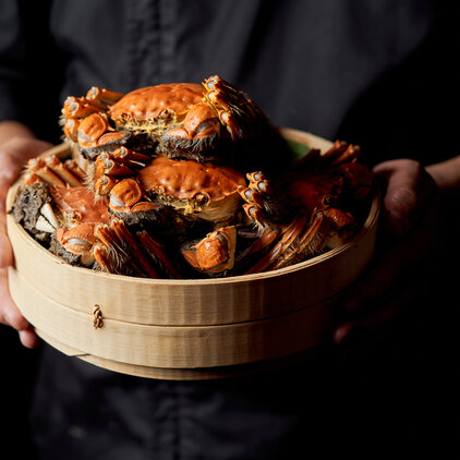 man holding a basket of steamed hairy crabs