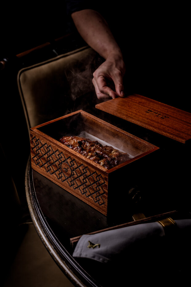 Mott 32's signature applewood smoked barbecue iberico pork with yellow mountain honey, placed in a wooden box